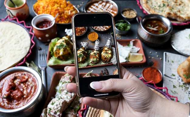 Hands of a blogger taking a photo of Indian food to share on social networks