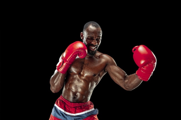 Hands of boxer over black background. Strength, attack and motion concept. Fit african american model in movement. Afro muscular athlete in sport uniform. Sporty man during boxing