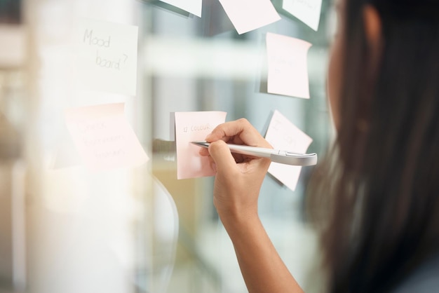 Hands brainstorming and woman writing notes for office schedule agenda and mindmap goals at window Closeup female employee planning ideas at glass for solution information and strategy objectives