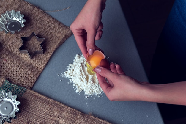 Hands break a chicken egg into flour 