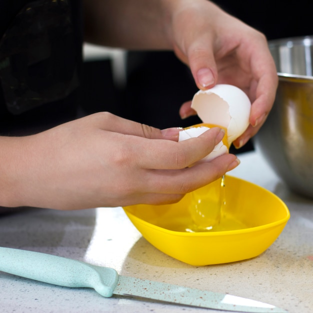 Hands break a raw egg. Separation of egg white from yolk