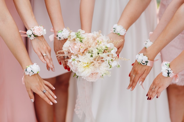 Hands of the bride and bridesmaids with flowers in pink shade