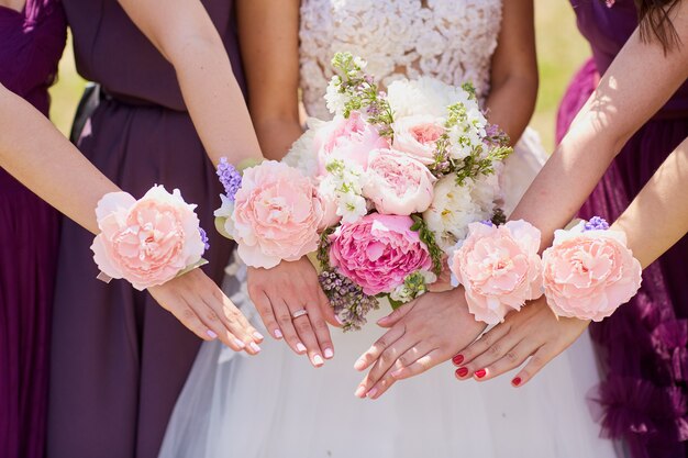 Hands of the bride and girlfriend with decorative flowers