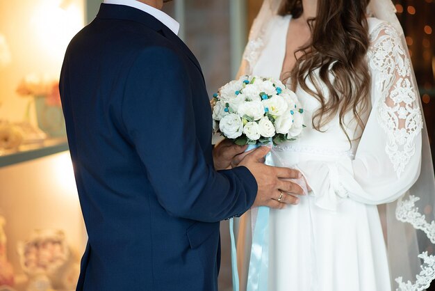 Hands of the bride and groom on the background of a bouquet closeup newlyweds wedding