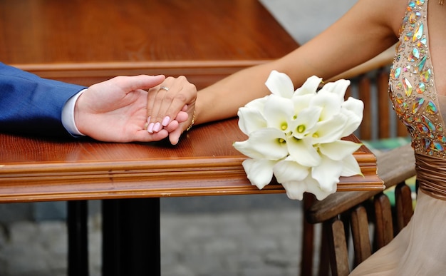 Hands of the bride and groom on the background of a wedding bouq