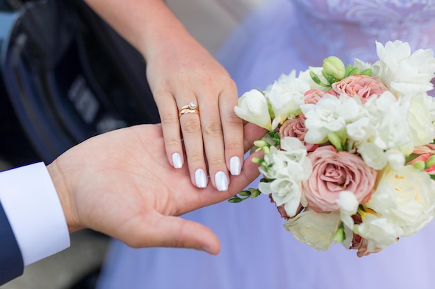 Hands of bride and groom with rings on wedding bouquet Marriage concept