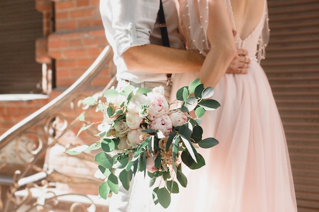 Hands of the bride and groom with wedding bouquet of flowers. fine art photography.