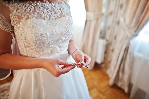 Hands of bride with earrings on hands at wedding day