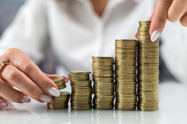 Hands of business woman taking several coins from a coin slide glass modern office table