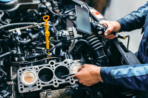 Hands of car mechanic check the vehicle engine with technical endoscope with rotary camera