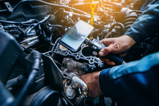 Hands of car mechanic check the vehicle engine with technical endoscope with rotary camera