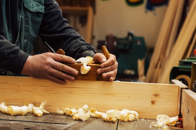 Hands of a carpenter planed wood