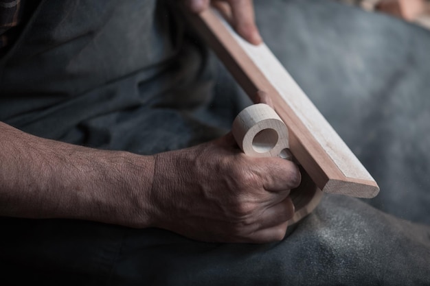 Hands carving cup from wood, working with chisel close up. Wooden workshop. Process of making wooden kitchenware High quality photo