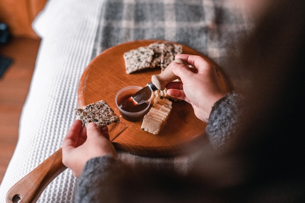 Photo hands of caucasian girl in woolen sweater spreading juicy barbecue sauce from a small plastic