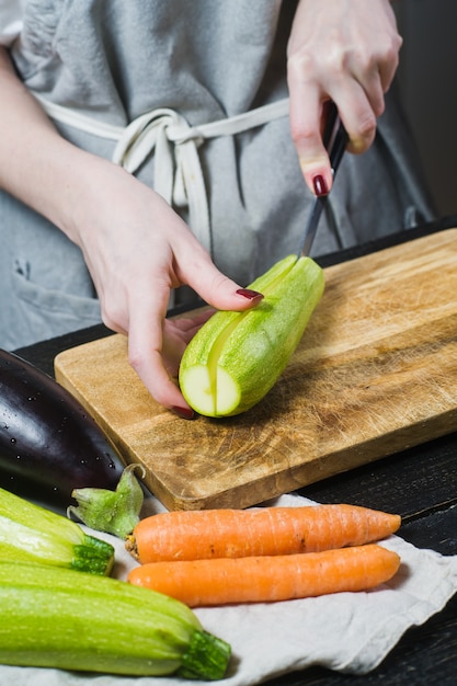 Hands chef cut zucchini on a wooden chopping Board. 