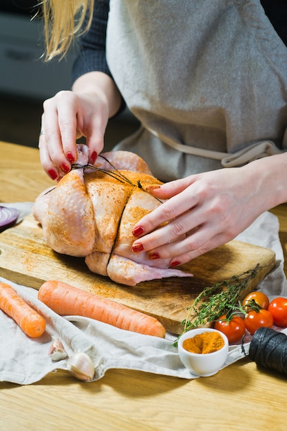 The hands of the chef rubbed the raw chicken with spices.