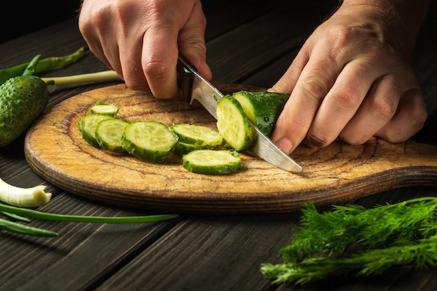 Hands of a chef with a knife while cooking in a restaurant kitchen