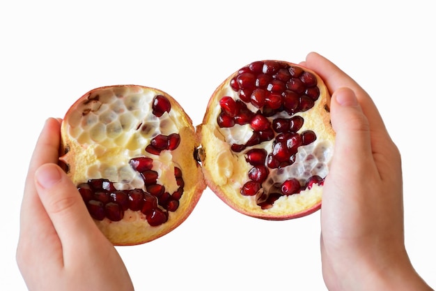 Hands of a child holding a pomegranate fruit broken in two on a white background