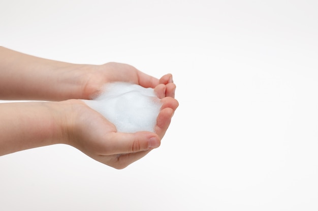 Hands of child on white in white foam from antibacterial soap