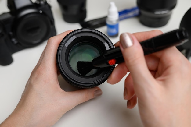 Photo hands cleaning the lens of a digital camera from dust with a special cleaning brush