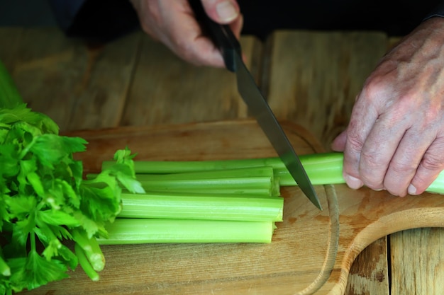 The hands of the cook cut the stalks of celery Fresh celery