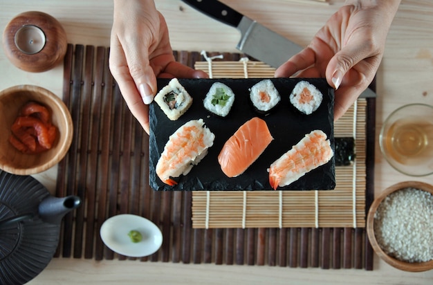 Hands cooking sushi with rice, salmon and nori