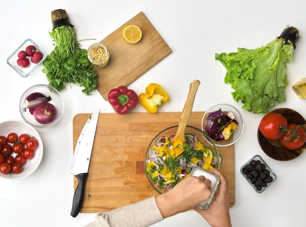 Photo hands cooking vegetable salad on kitchen table