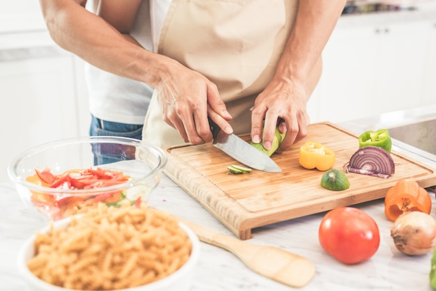 Hands of couple or lovers cooking  and slicing vegetables