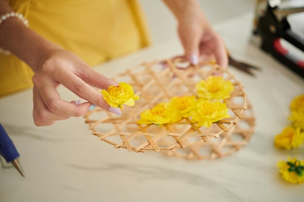 Hands of creative woman making tet decorations with artificial yellow apricot flowers