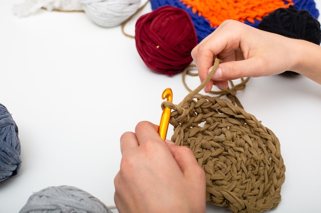 Hands crocheting with brown wool