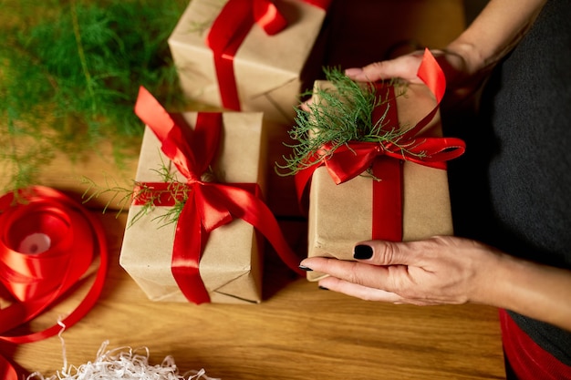 Hands of cropped unrecognisable woman packing Christmas present