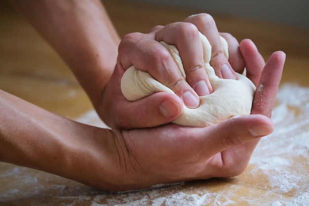 Hands crumples in the palms a lump of dough during cooking and making bread