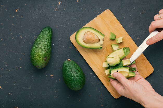 Photo hands cutting avocado on a cutting board