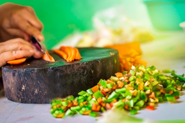 Hands cutting carrot pieces on a homemade chopper Close up of hands chopping carrots in a wooden chopper Concept of hands cutting vegetables in a wooden chopper