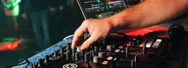 Hands of a DJ in a booth playing on the mixer