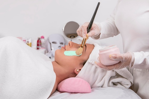 hands of Esthetician applying mask for facial cleansing treatment skin care concept