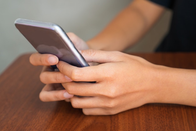 Hands of female student using smartphone at lesson