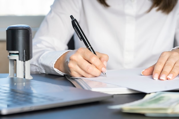 Hands of a financial worker in a white shirt signing a document. Workflow in accounting close-up.