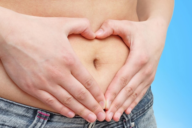 Hands folded on his stomach in the form of a heart. on a blue background