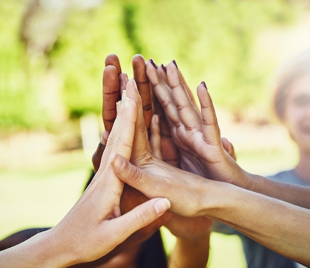 Hands friends and high five at a park for teamwork collaboration and volunteering motivation Hand connection people and volunteer group outdoor for community clean up and charity mission help