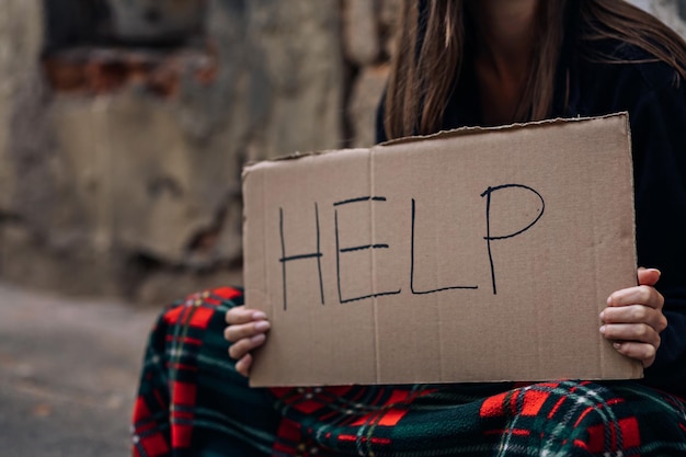 In the hands of the girl holding a plate with the inscription ask for help to caring people