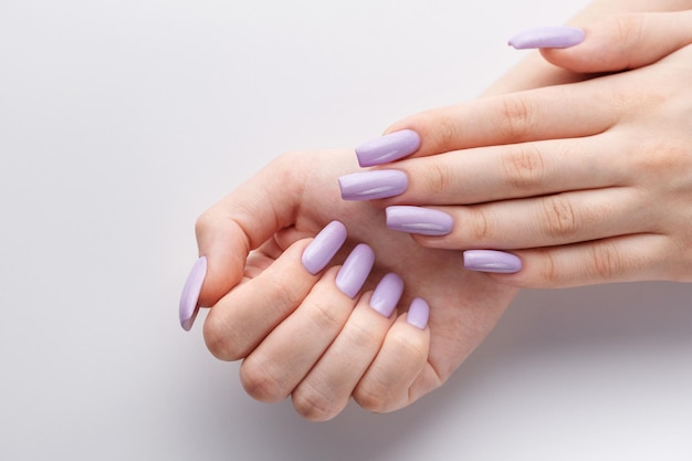 Hands of a girl with a soft purple manicure on a white background