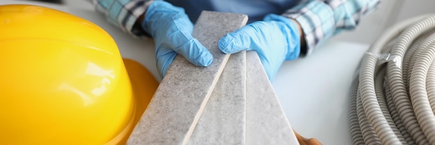 Hands in gloves hold samples of stone tiles closeup