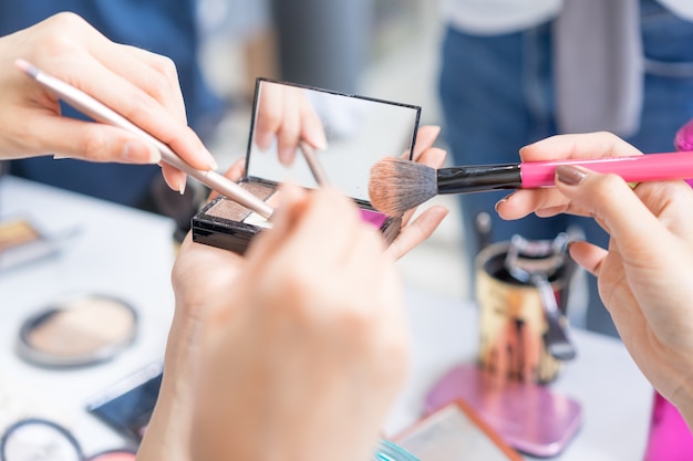 Hands of group girls holding makeup brush and palette for makeup, Beauty concept