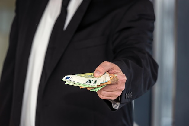 Hands of handsome businessman man in suit with euro banknotes in hands on business office