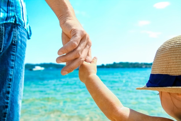 A Hands of a happy parent and child in nature by the sea on a journey background