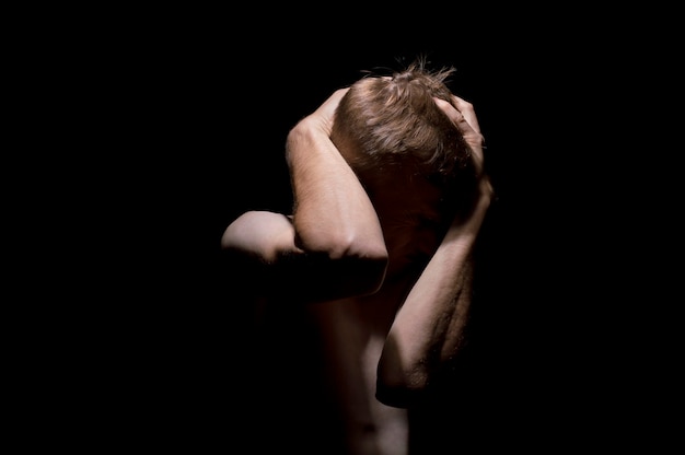 Hands on head, black and white dramatic photo of a man