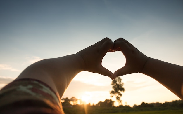 Hands in heart form love, silhouette hand make heart form with sun set