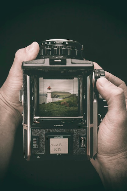 Photo hands hold a medium format film camera dark background