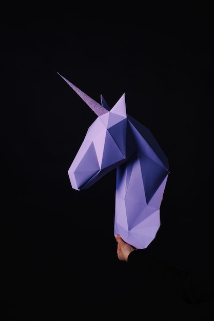 Hands hold a turquoise Unicorn. Artwork. 3d papercraft model of a unicorn. Copy space